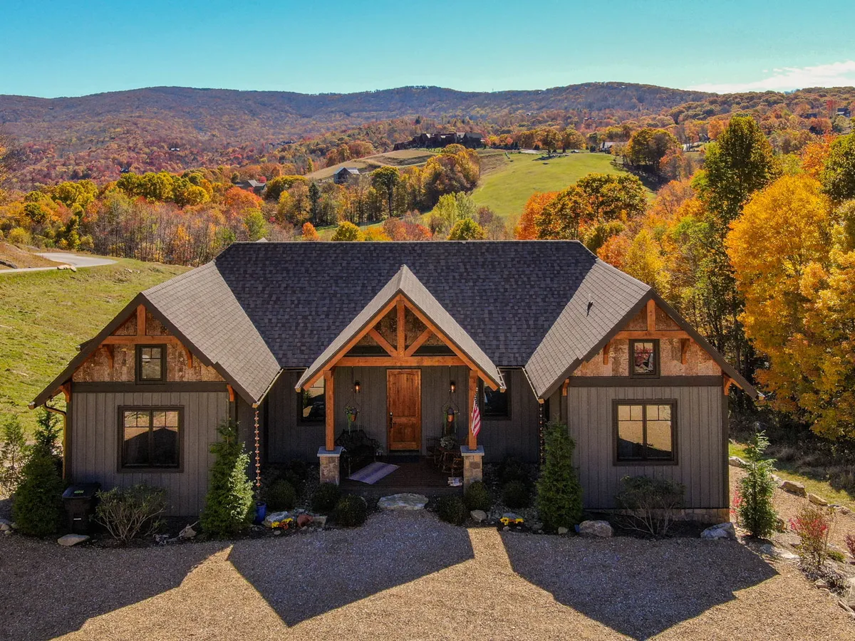 This image captures the home's front entrance, framed by vibrant autumn foliage and a lush landscaped garden, with a stunning mountain backdrop visible in the distance. It radiates a sense of arrival and hints at the natural adventures awaiting just beyond the doorstep.