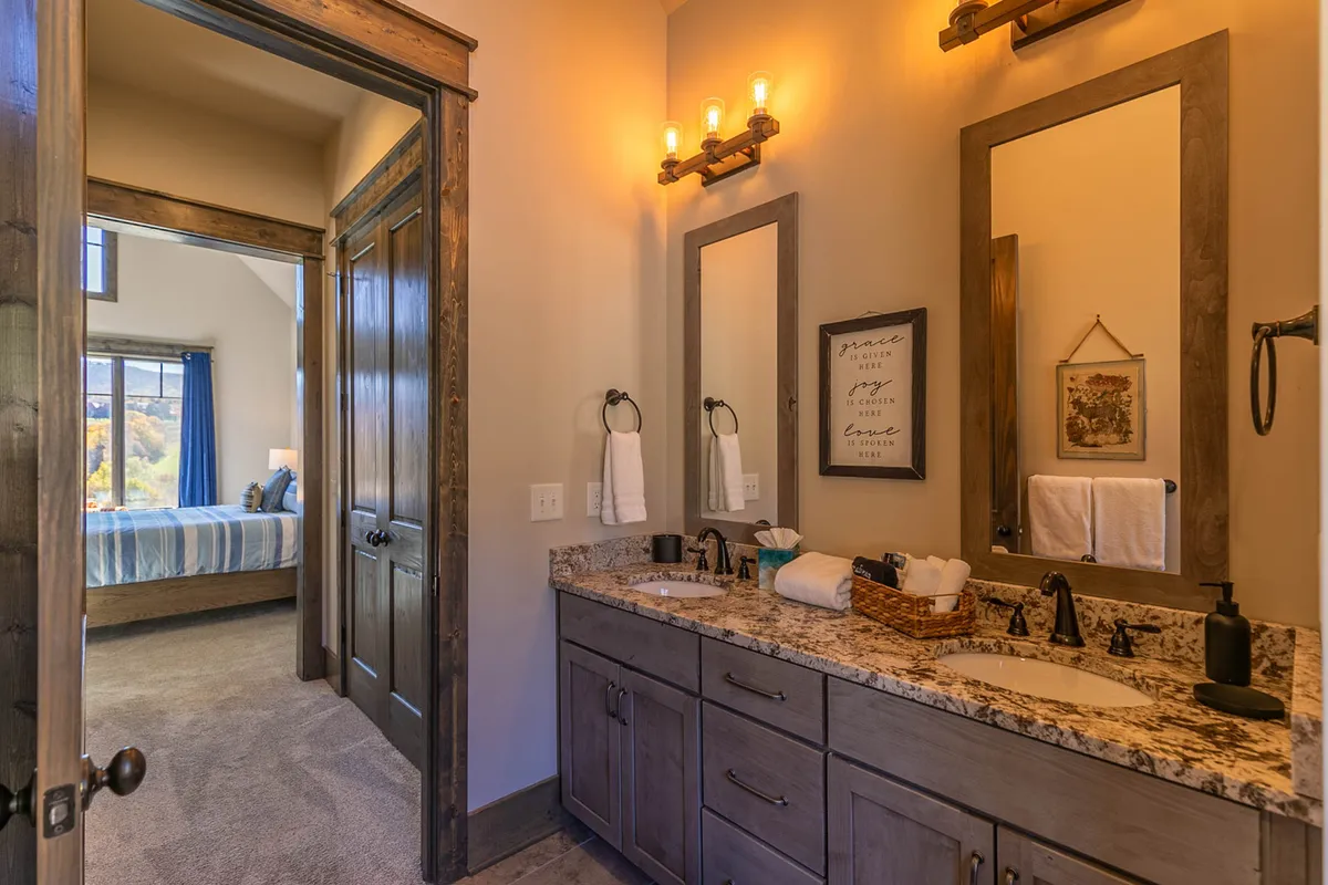 A serene bathroom featuring a double sink vanity, well-lit mirrors, and decorative accents. The space feels spacious and modern, ideal for accommodating morning or bedtime routines for larger groups.