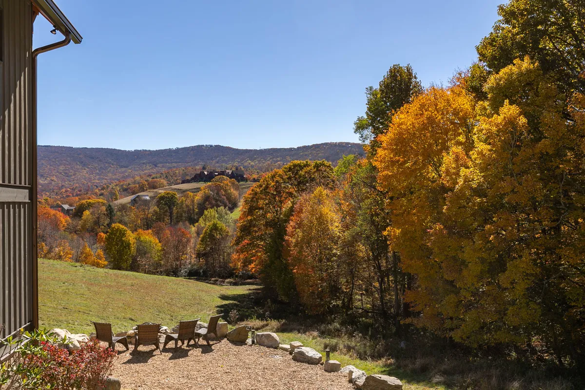 A breathtaking outdoor setting with colorful autumn trees, stone seating arranged around a fire pit, and vast mountain landscape views. Ideal for gatherings, sunset watching, or relaxing after a day of exploring.