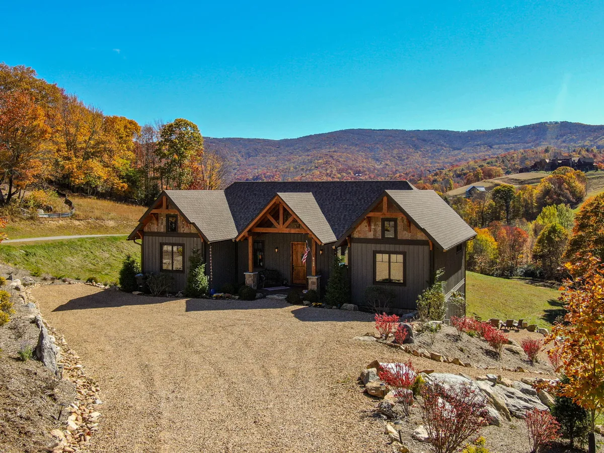 An inviting view of the house facade, its front porch, and the surrounding trees and landscaping. The spacious outdoor area hints at room for dogs to play and families to enjoy nature together. The serene, wooded environment is clearly visible and complements the section’s emphasis on pet-friendly outdoor adventure.
