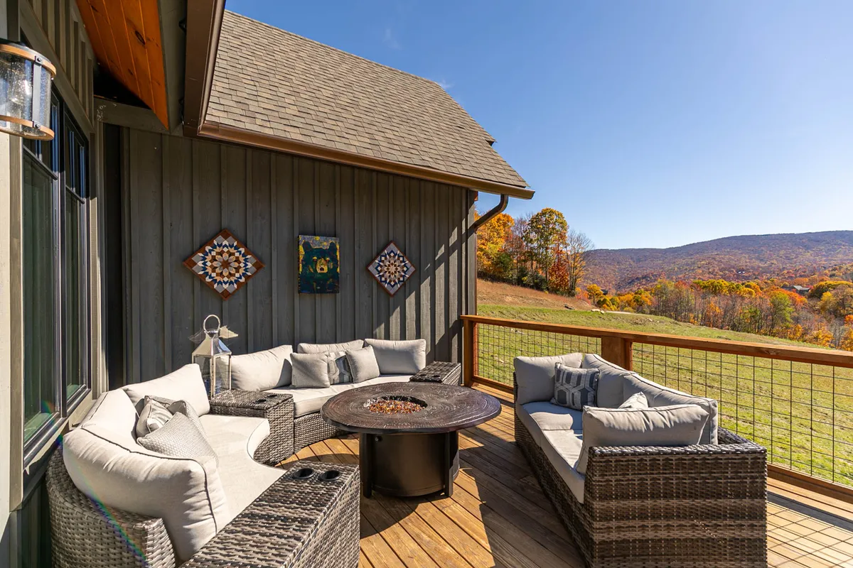 A panoramic view of a comfortable outdoor lounge area with a fire pit, plush seating, and a striking mountain vista in the background. Decorative touches add warmth and personality.