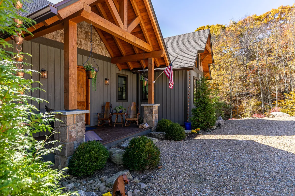 This exterior shot features the front porch of Dreamweaver with inviting rocking chairs, an American flag, and a tastefully landscaped garden. The cozy, welcoming atmosphere is highlighted by the open porch, which offers a direct connection to the natural surroundings and serves as an ideal spot to relax with pets after a day of exploring.