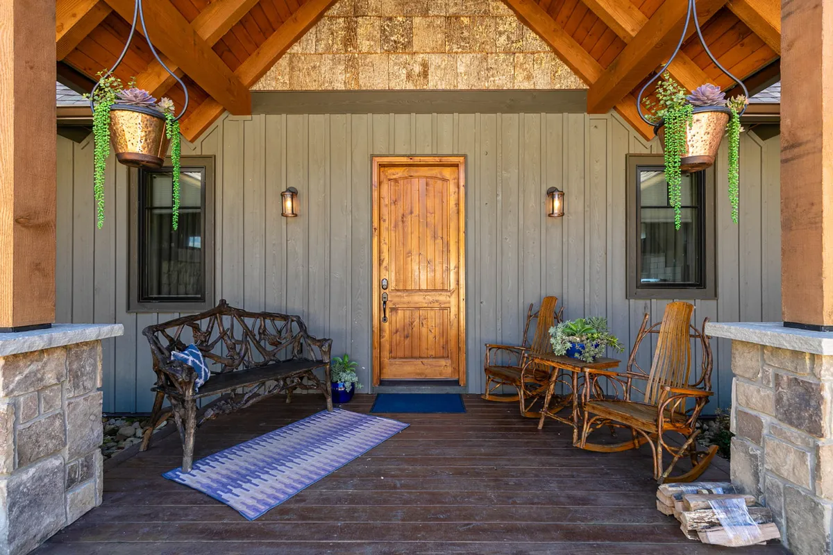 A charming view of the home's wooden front door with rocking chairs and decorative plants on the porch, inviting guests to sit and enjoy the peaceful outdoor environment.
